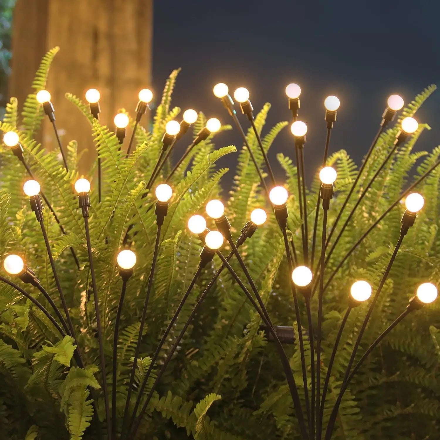 Solar firefly lights glowing among garden ferns at dusk