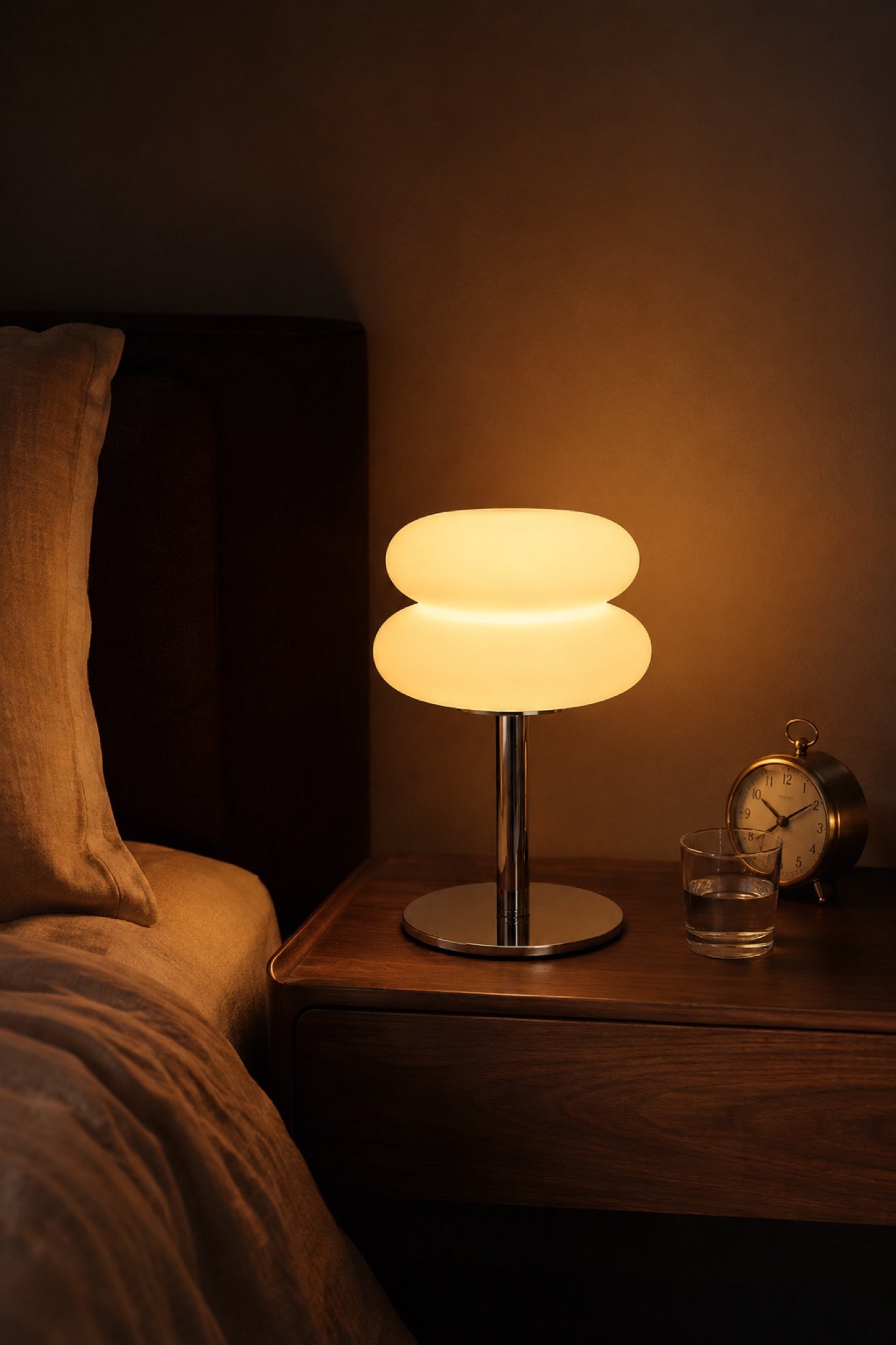 The Mushroom lamp glowing on a walnut bedside table with a brass alarm clock