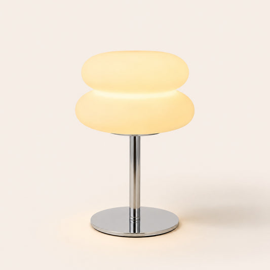 The Mushroom opal glass lamp with chrome stem, lit, on warm porcelain background