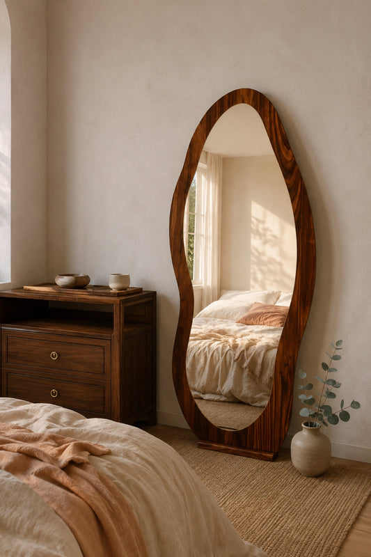 The Wave wavy walnut full-length mirror leaning against a limewash wall in golden morning light