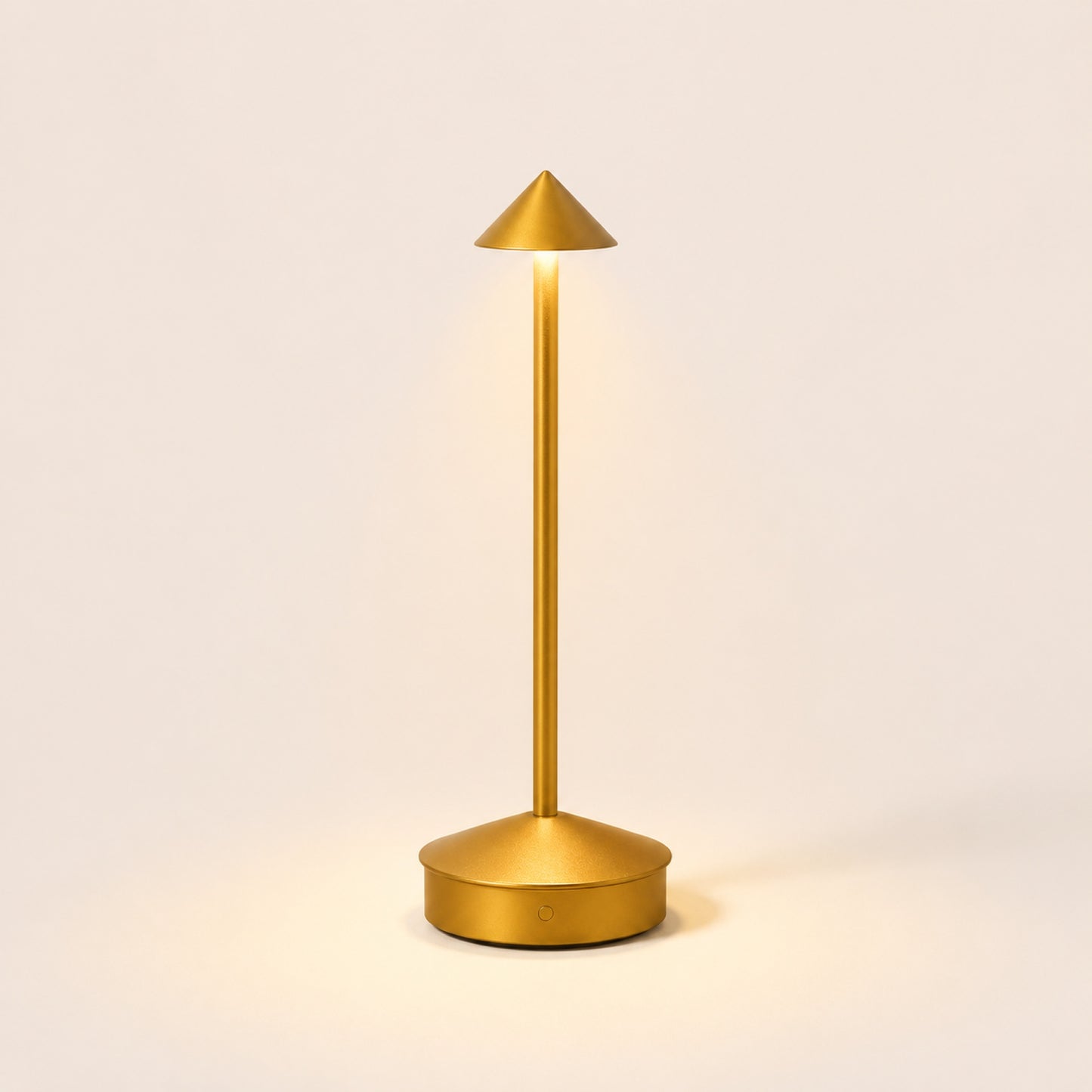 The Wren cordless table lamp in Brass Gold, lit, on warm porcelain background