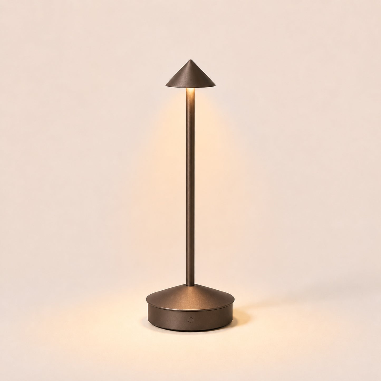 The Wren cordless table lamp in Bronze, lit, on warm porcelain background