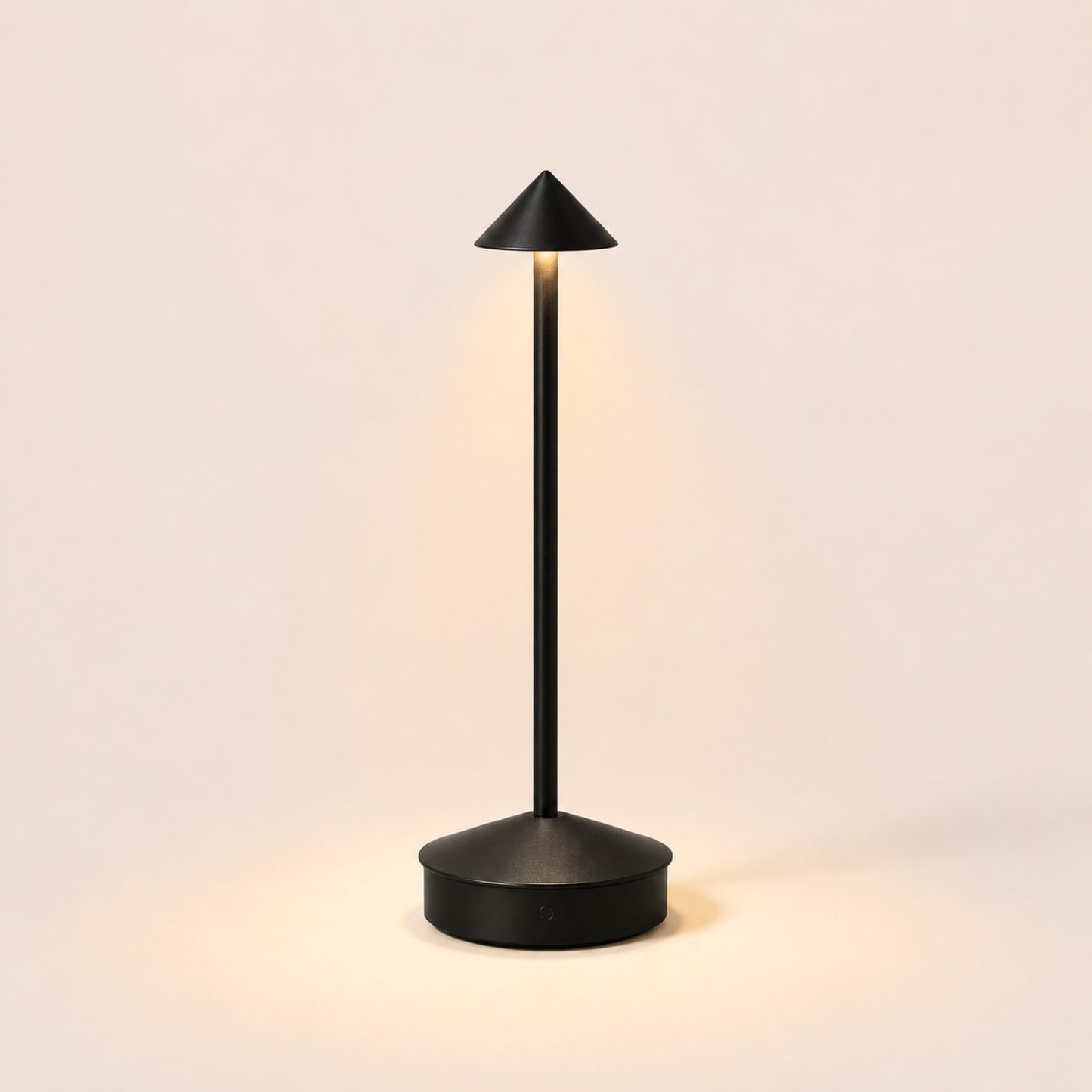 The Wren cordless table lamp in Matte Black, lit, on warm porcelain background