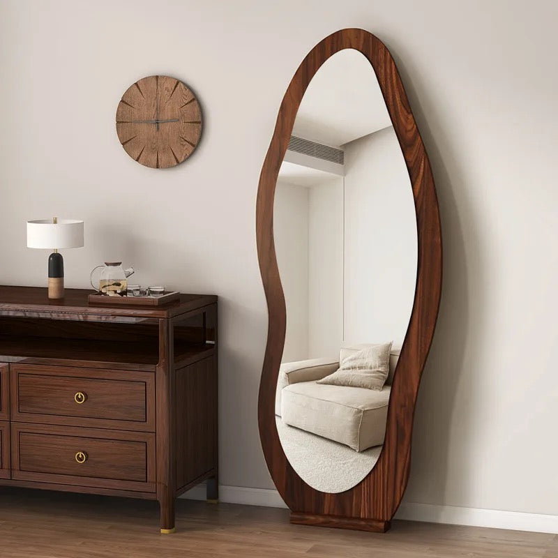 The Wave mirror in walnut beside a wooden dresser